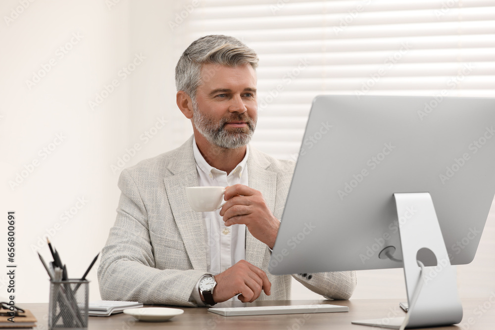 Professional accountant with cup of coffee working at wooden desk in office Professional accountant with cup of coffee working at wooden desk in office