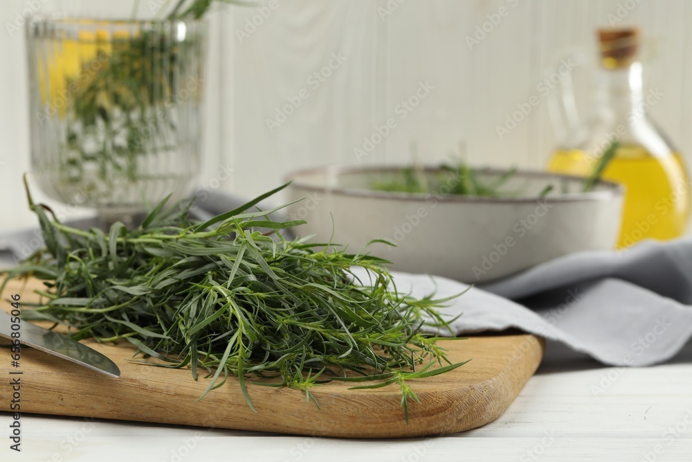 Fresh tarragon sprigs and knife on white wooden table, closeup Fresh tarragon sprigs and knife on white wooden table, closeup