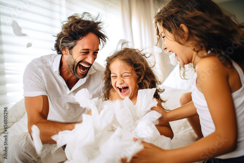 Fototapeta Beautiful young family having a pillow fight in the bedroom and enjoying quality time together, fun family bonding
