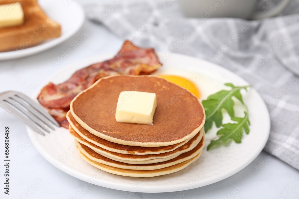 Tasty pancakes served with fried egg and bacon on white table