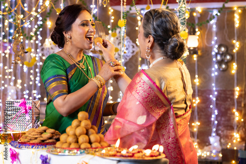 Photography Daughter in law feeds mother in law Laddoo during Diwali celebrations