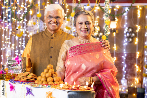 Happy Indian Senior couple decorating with Diya oil lamps on the occasion of Diwali festival celebration © G-images