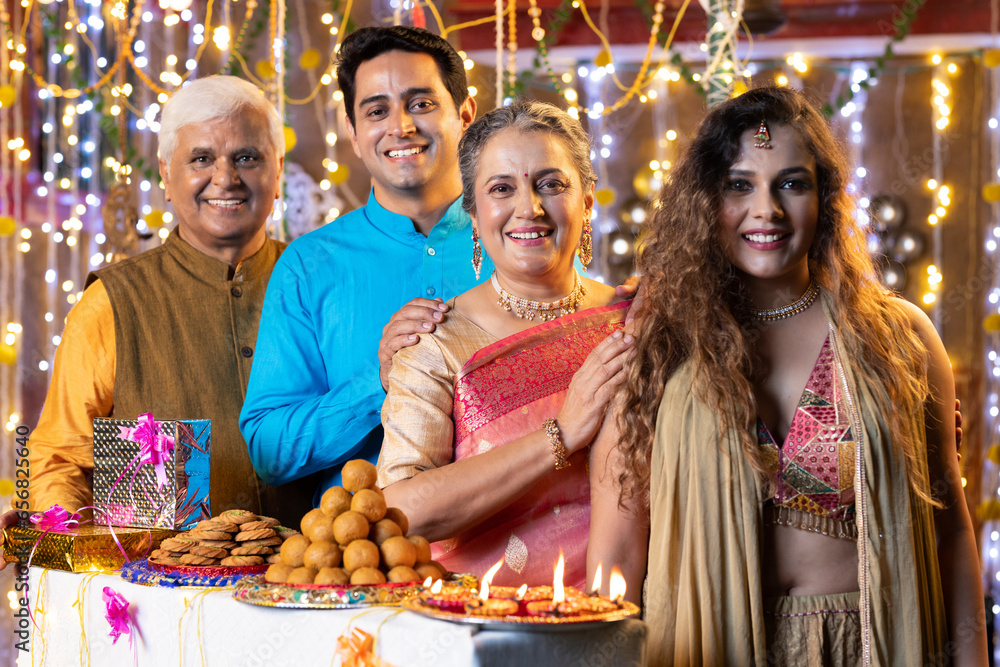 Happy indian family with sweet food and gifts on the occasion of Diwali festival celebration at home.