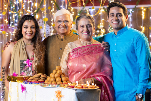 Happy indian family with sweet food and gifts on the occasion of Diwali festival celebration at home.