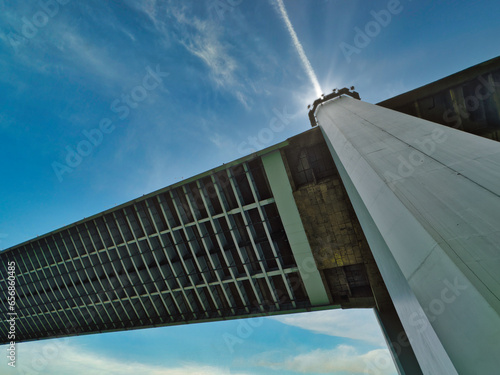 Beautiful abstract low angle view of suspension big concrete column and steel structure bridge under sparkling sun ray on the top and blue cloud sky