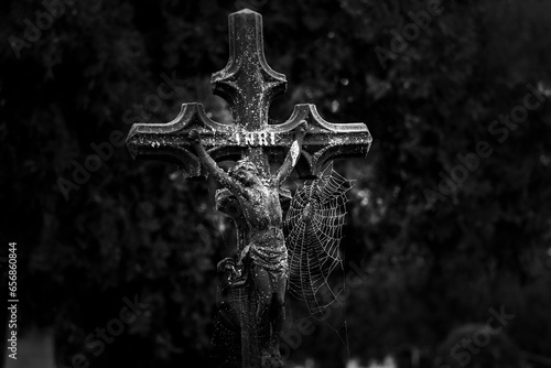 Cross with spider web in cemetery. Halloween background