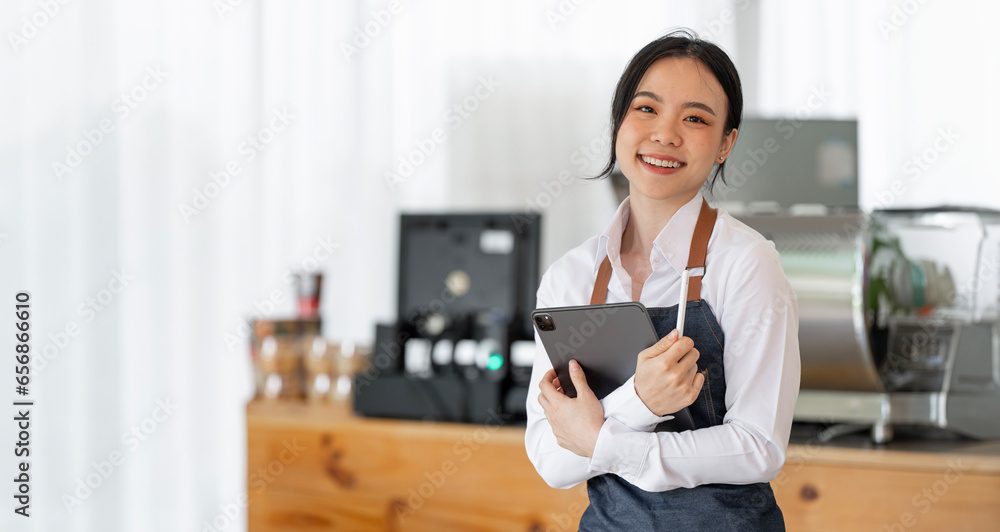 Cheerful young waitress waiting for clients at coffee shop. Successful small business owner in casual wearing blue apron standing in her shop. Cheerful young waitress waiting for clients at coffee shop. Successful small business owner in casual wearing blue apron standing in her shop.