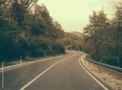 Driving on a highway in autumn forest. Road in mountain wood in fall. Adventure and travel concept.