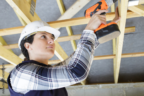 young builder working on wooden roof joist photo