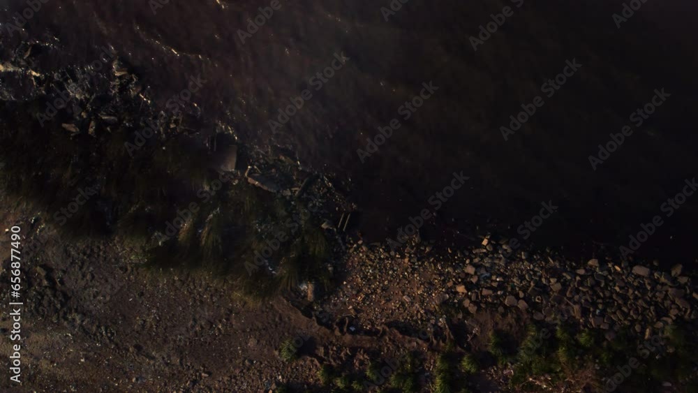 The drone circles over the shore, flies along the shore, stones on the sand The drone circles over the shore, flies along the shore, stones on the sand