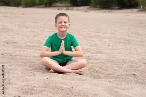 boy meditates on the beach. sits cross-legged. yoga class.
