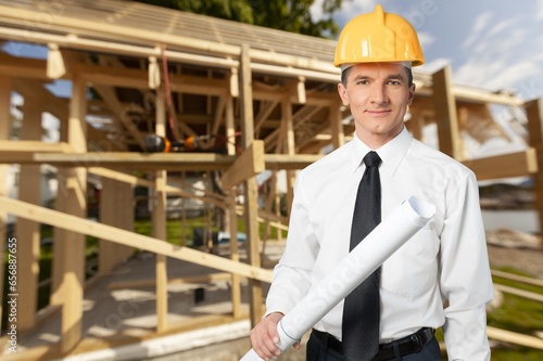 Construction engineer with blueprints checking building site