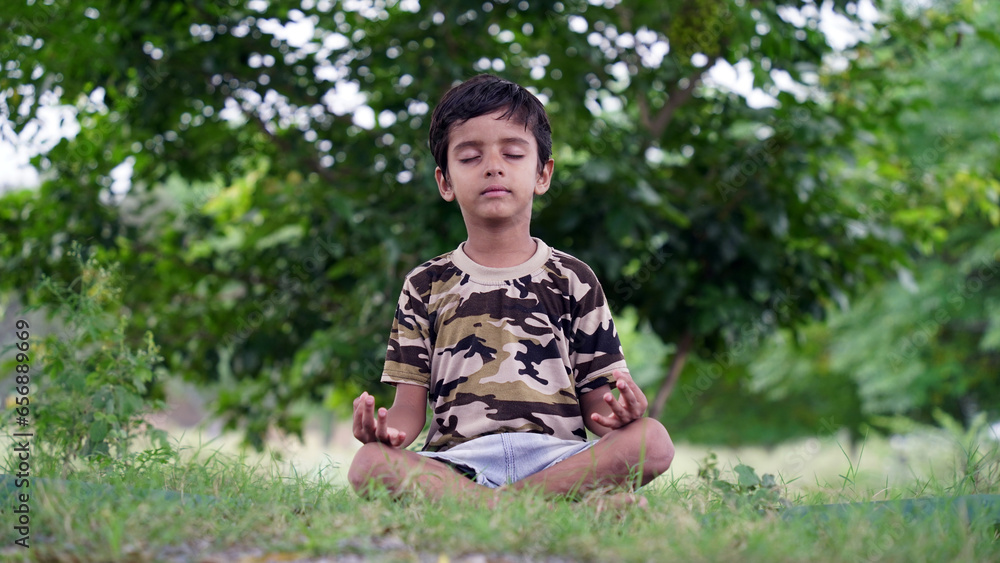 Little Indian boy practicing yoga in home garden. kid doing gymnastic exercises or meditating, health concept