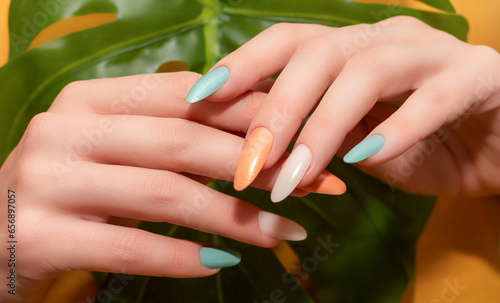 Female hands with glitter nail polish. Green and orange nail design with two shades. Women hands with sparkle colored manicure.