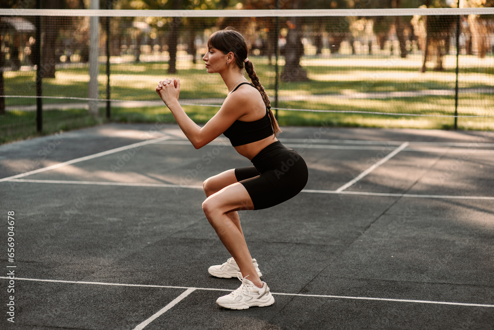 A young girl with an athletic figure is doing fitness at the sports ground. fitness trainer. Slim body