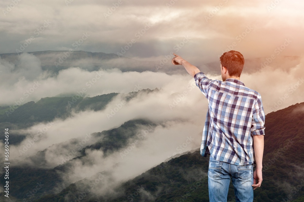 Person stands on a mountain peak looking in beautiful view Person stands on a mountain peak looking in beautiful view