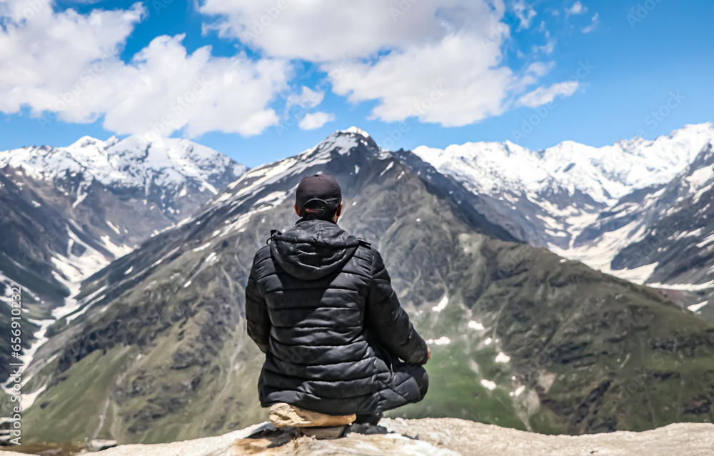 person sitting and doing meditation on the top of the mountain