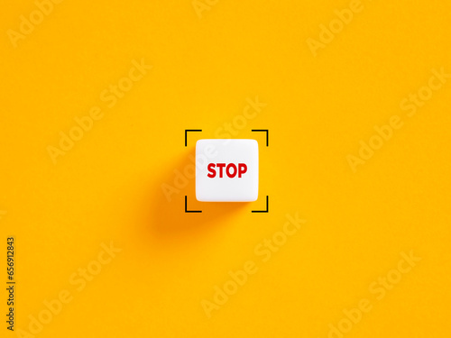 Stop push button. The word stop on white cube on yellow background.