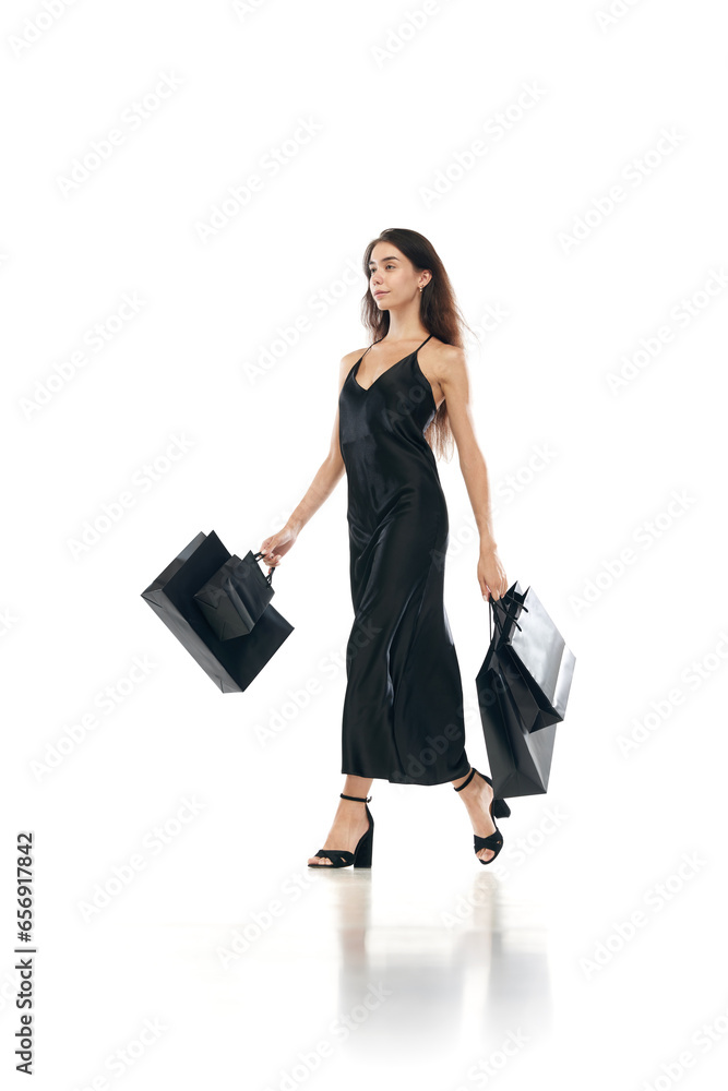 Cyber monday concept. Full lenght portrait of women wearing black long dreass holding bags in hands going shopping mall isolated on white background