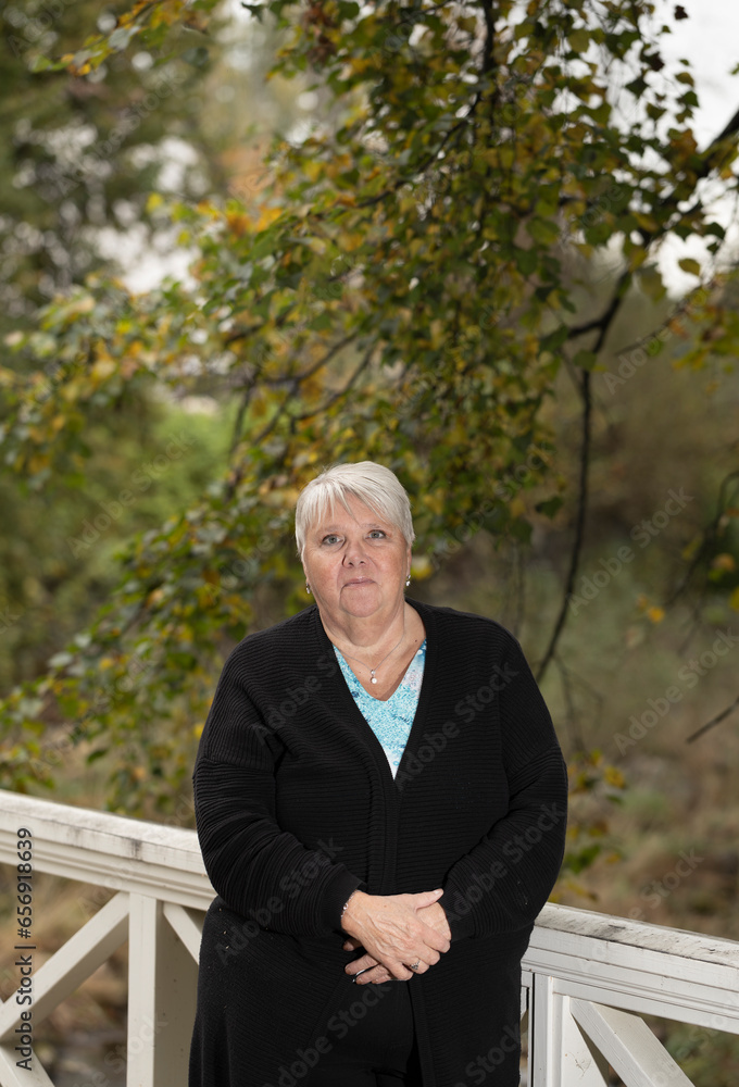 Elder woman standing on a wooden bridge Elder woman standing on a wooden bridge