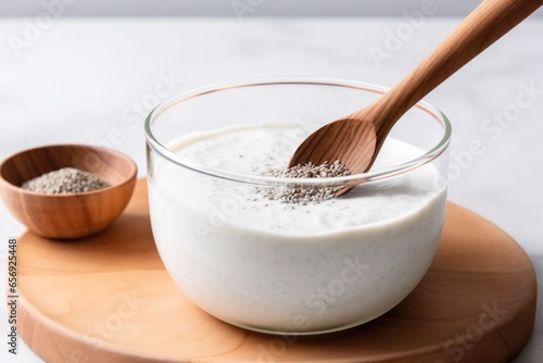 stirring chia seeds into a coconut yogurt with a wooden spoon