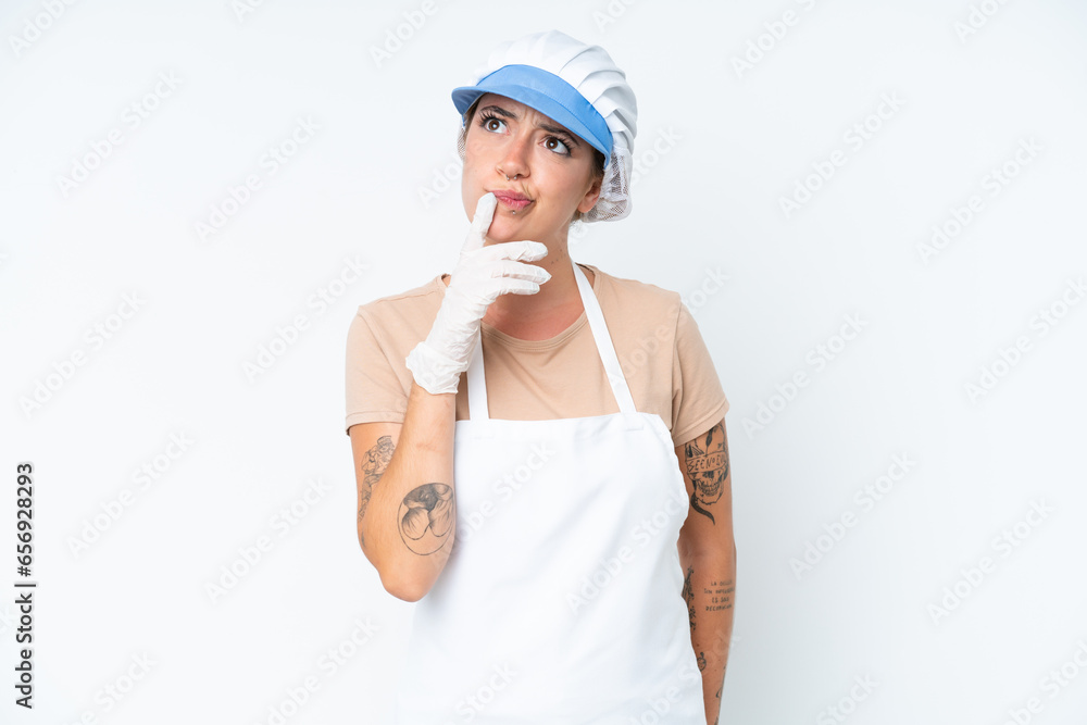 Fishmonger wearing an apron and holding a raw fish isolated on white background having doubts while looking up Fishmonger wearing an apron and holding a raw fish isolated on white background having doubts while looking up