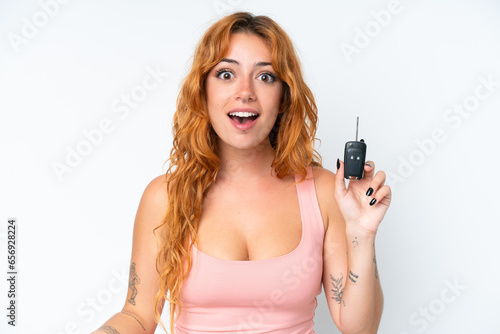 Young caucasian woman holding car keys isolated on white background with surprise and shocked facial expression