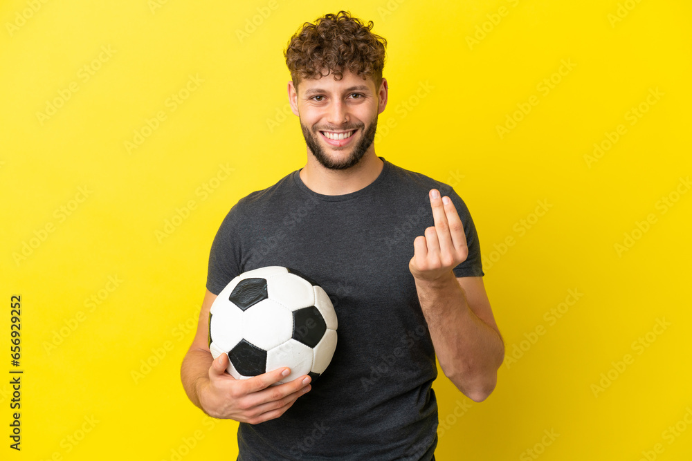 Handsome young football player man isolated on yellow background making money gesture
