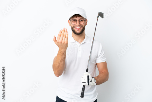 Handsome young man playing golf isolated on white background inviting to come with hand. Happy that you came
