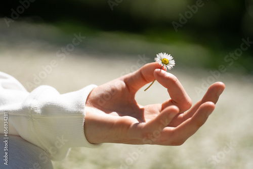 Close-up of teenage girl holding daisy and gesturing mudra