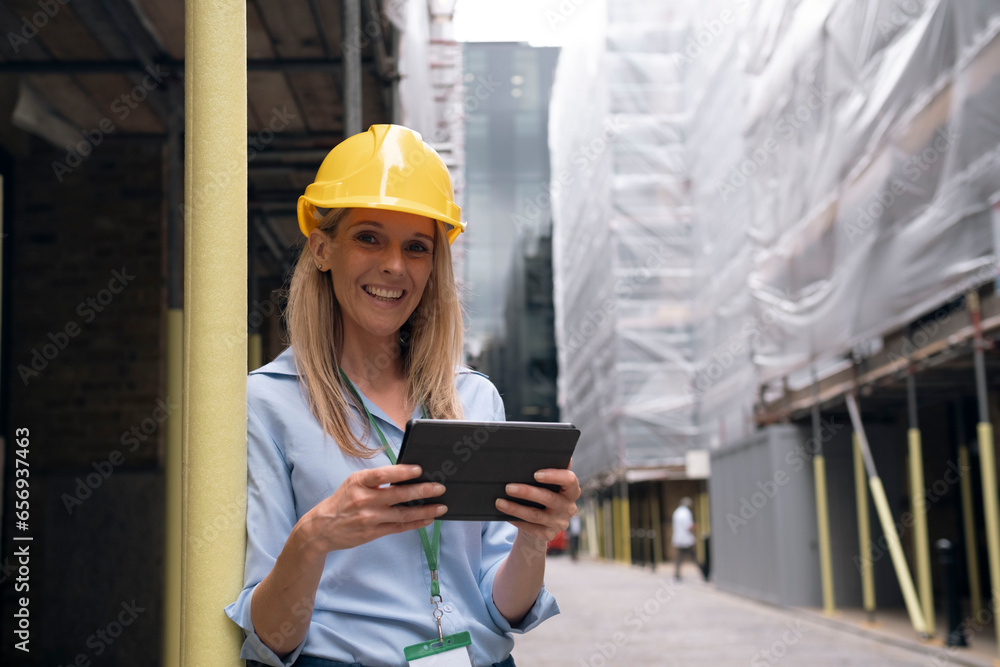 Smiling engineer holding tablet PC at construction site Smiling engineer holding tablet PC at construction site