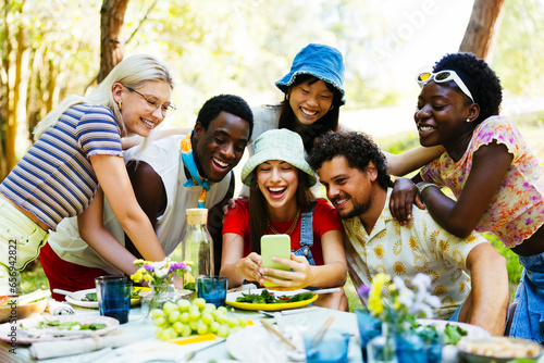 Happy woman using smart phone with friends in garden photo