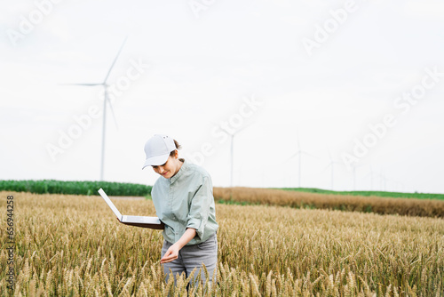 Smiling agronomist examining crops at field photo