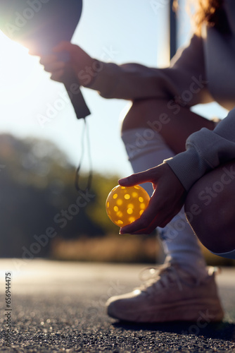 Pickleball player holding a ball and a racket in hands