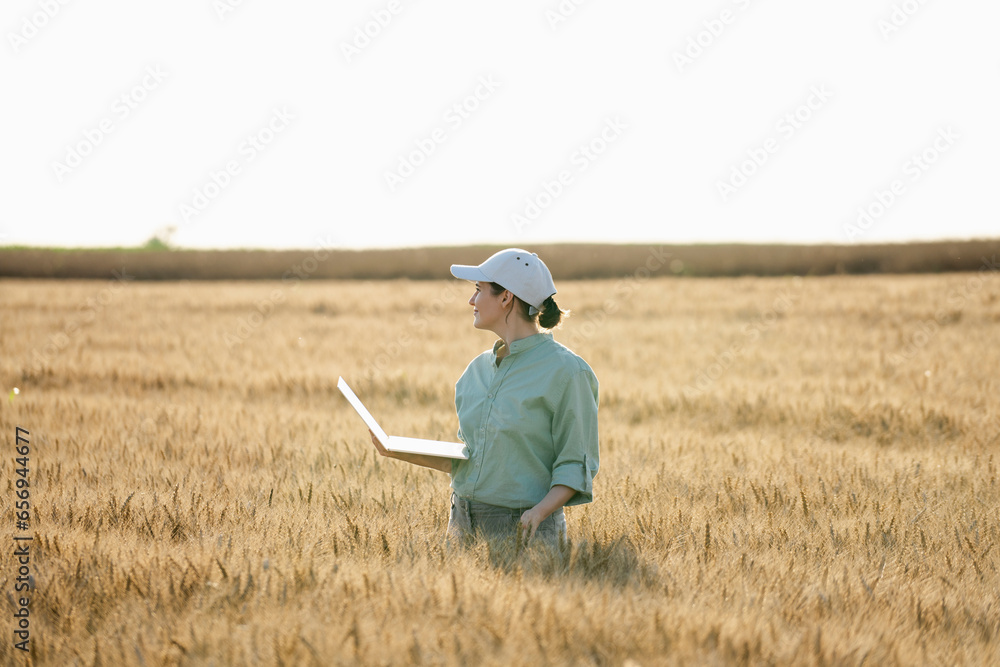 Farmer standing with laptop amidst wheat crop at field Farmer standing with laptop amidst wheat crop at field