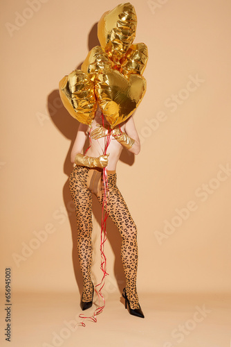 Shirtless woman wearing stocking and holding golden colored balloons photo