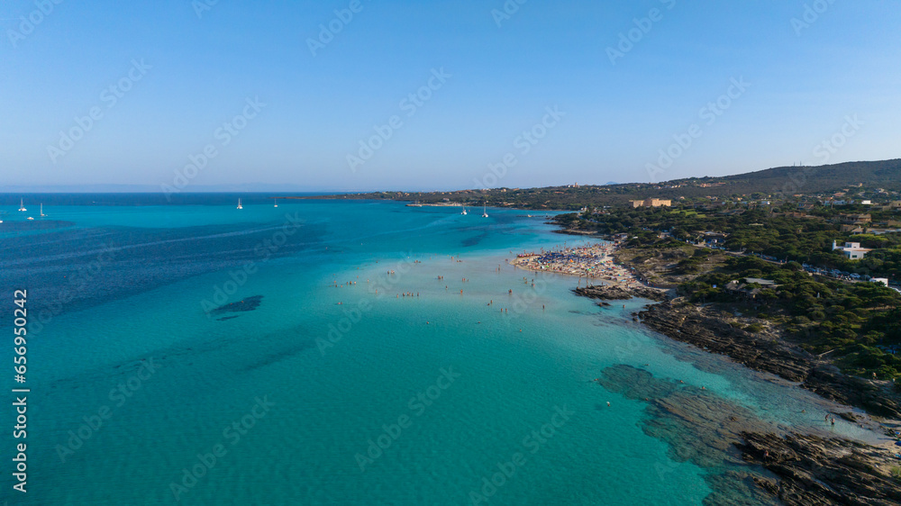 Aerial view of La Pelosa beach at sunny summer day. Stintino, Sardinia island, Italy. Drone view of sandy beach, playing people, clear blue sea.