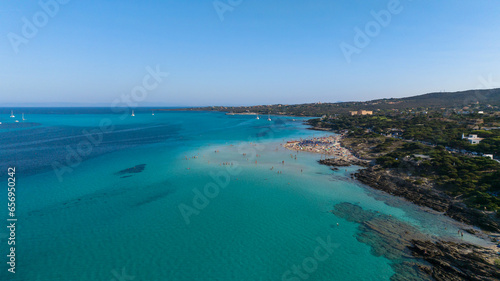 Aerial view of La Pelosa beach at sunny summer day. Stintino  Sardinia island  Italy. Drone view of sandy beach  playing people  clear blue sea.