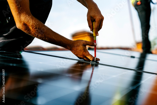 Hands of engineer using screwdriver to install solar panels photo