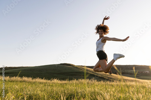 Cheerful woman jumping on sunny day photo