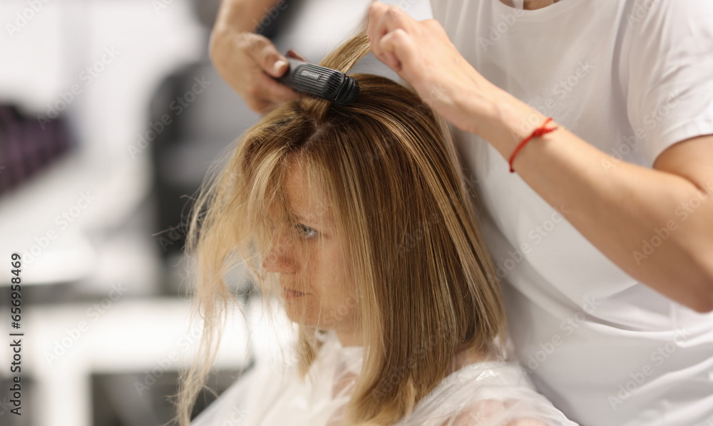 Pulling strands of hair with professional iron care. Keratin straightening and hair restoration Pulling strands of hair with professional iron care. Keratin straightening and hair restoration
