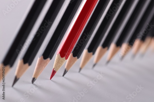 Red pencil separating row of black pencils. Business concept for leadership or thinking differently