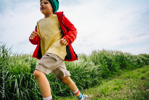 Boy in red jacket running by barley crop on field photo