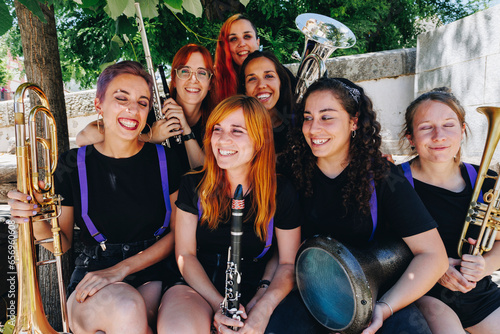 Cheerful women's folk music group sitting together holding wind instruments photo