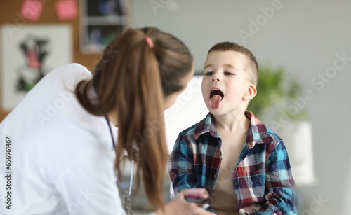 Doctor consults little boy with sore throat. Inflammation of tonsils of adenoids and tonsillitis in children photo