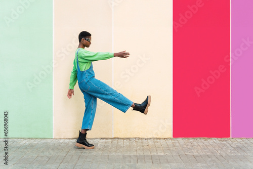 Woman wearing smart glasses gesturing in front of multi colored wall photo