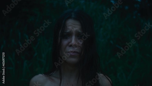 A tired, frightened girl with abrasions in a bloody dress cries looking at the camera photo