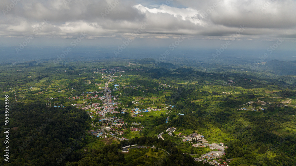 Top view of small town among the mountains with jungle and rainforest. Berastagi, Sumatra. Indonesia.