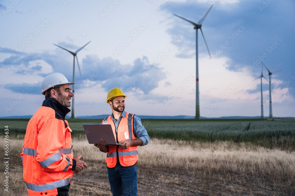 Smiling engineers with laptop at wind farm Smiling engineers with laptop at wind farm