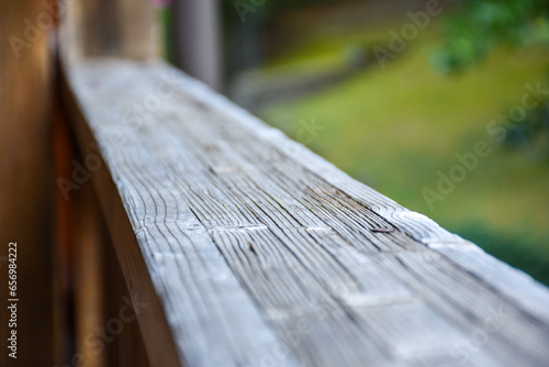 Wooden railing on the terrace outside. Detail on wood. Green landscape in the background